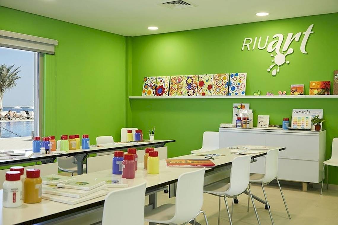 Ein grünes Klassenzimmer mit Riuart Schild, bunten Farben und Kunstmaterialien.