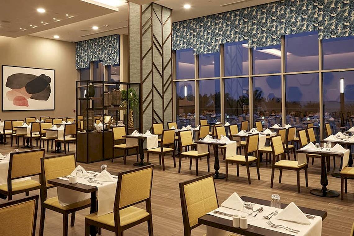 Innenansicht des Restaurants im Riu Dubai Hotel mit vollen Tischen und Stühlen.
