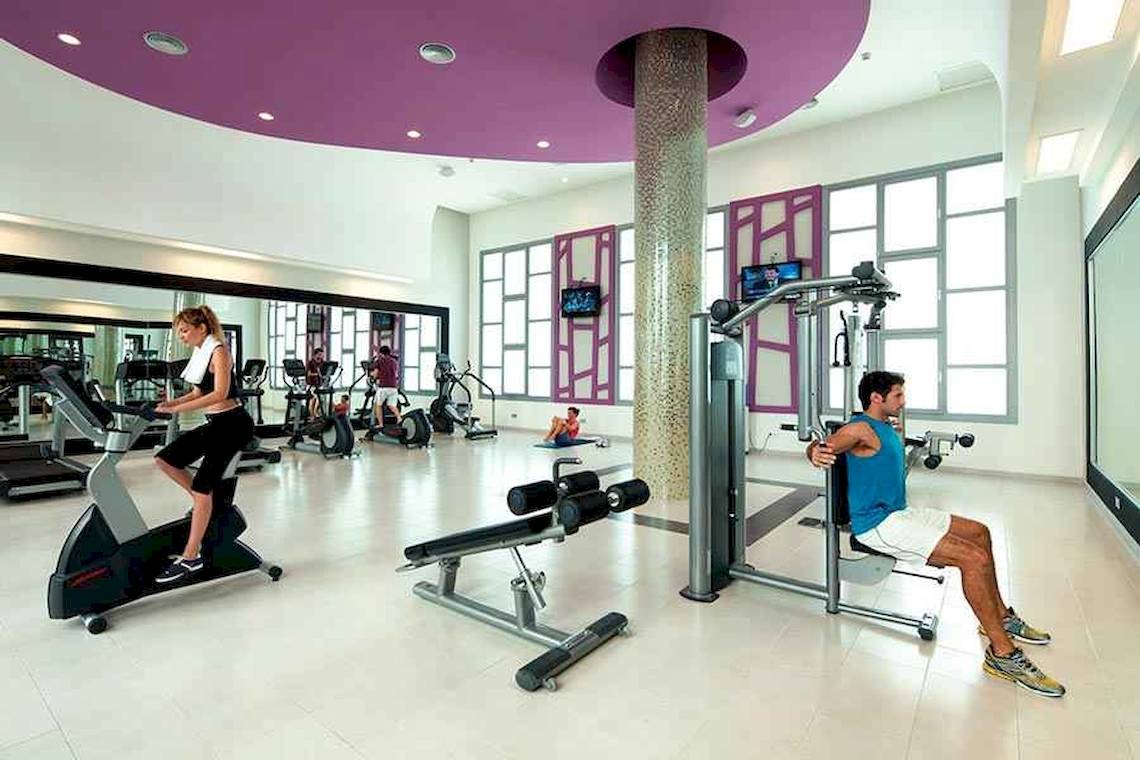 Fitnessstudio im Riu Palace Bavaro mit Geräten und Sportlern.