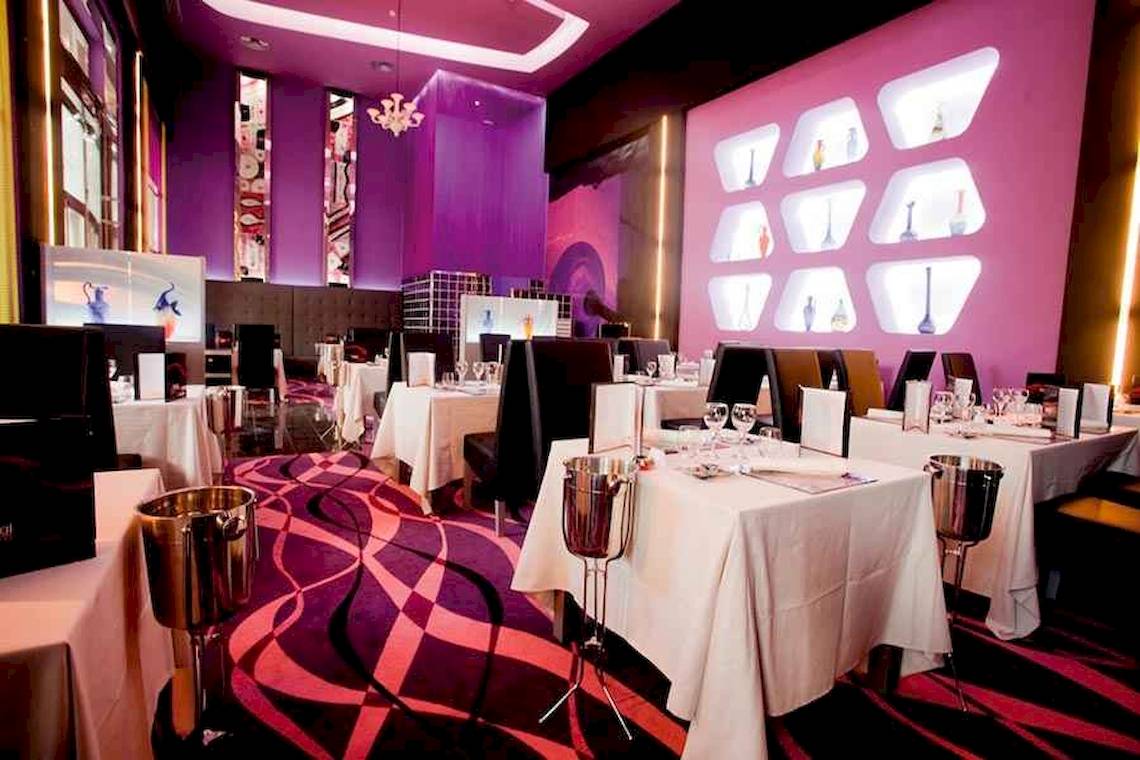 Innenansicht des Restaurants im Riu Palace Bavaro mit violetten Wänden und stilvollen Tischarrangements.