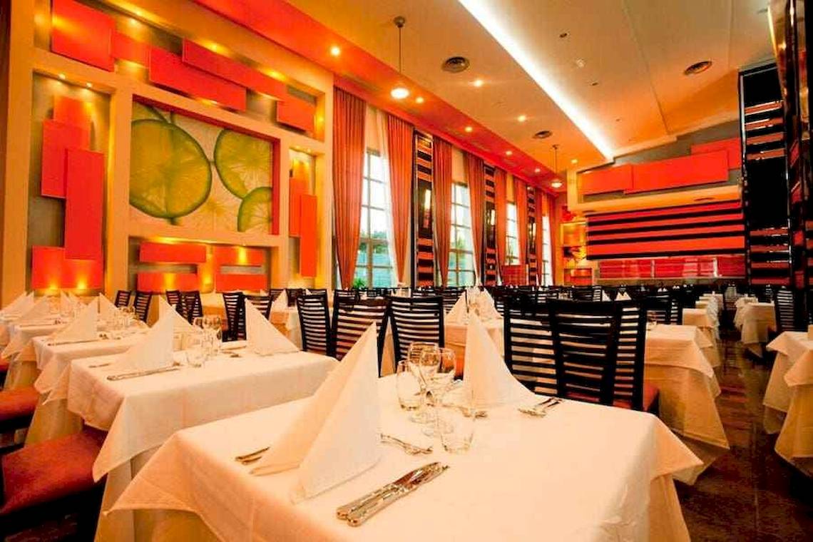 Innenansicht des Restaurants im Riu Palace Bavaro Hotel mit gedeckten Tischen und orange-grauer Wandgestaltung.