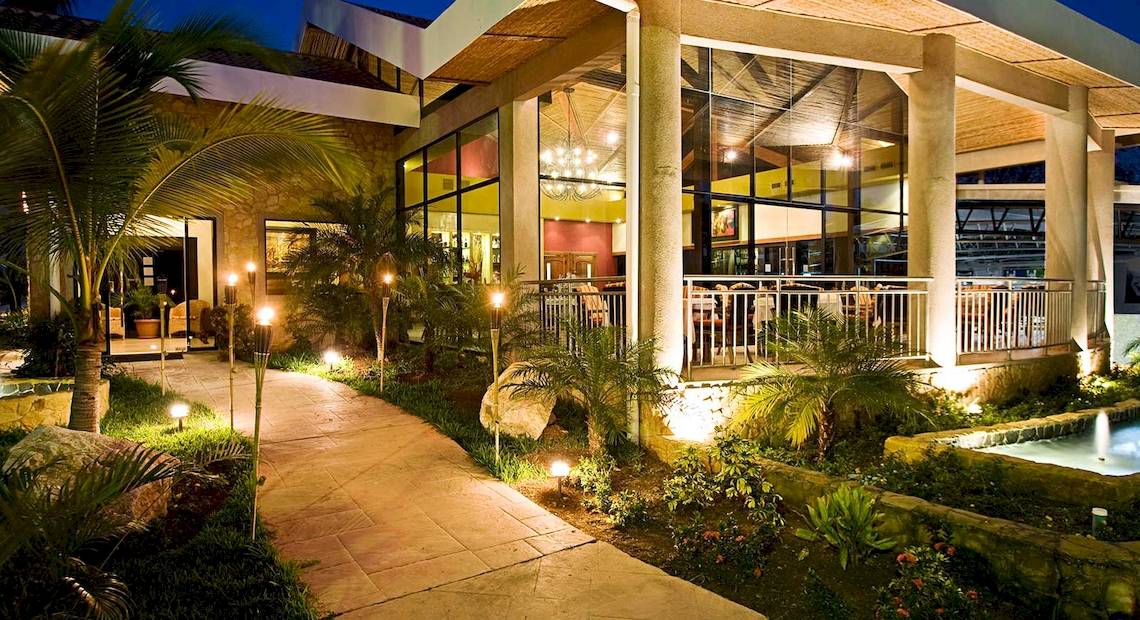 Abendliche Ansicht des Hotels Occidental Tamarindo mit beleuchtetem Gehweg und Terrasse.