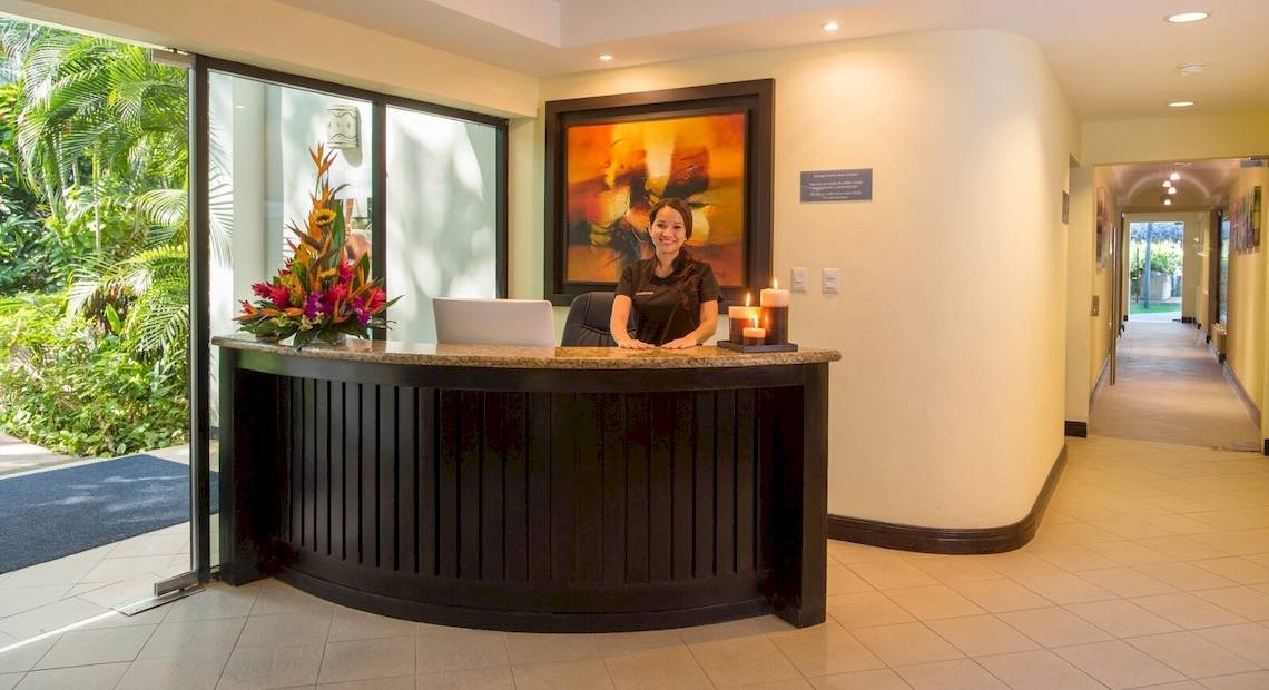 Rezeptionistin des Occidental Tamarindo Hotels lächelt vor einem großen Gemälde.