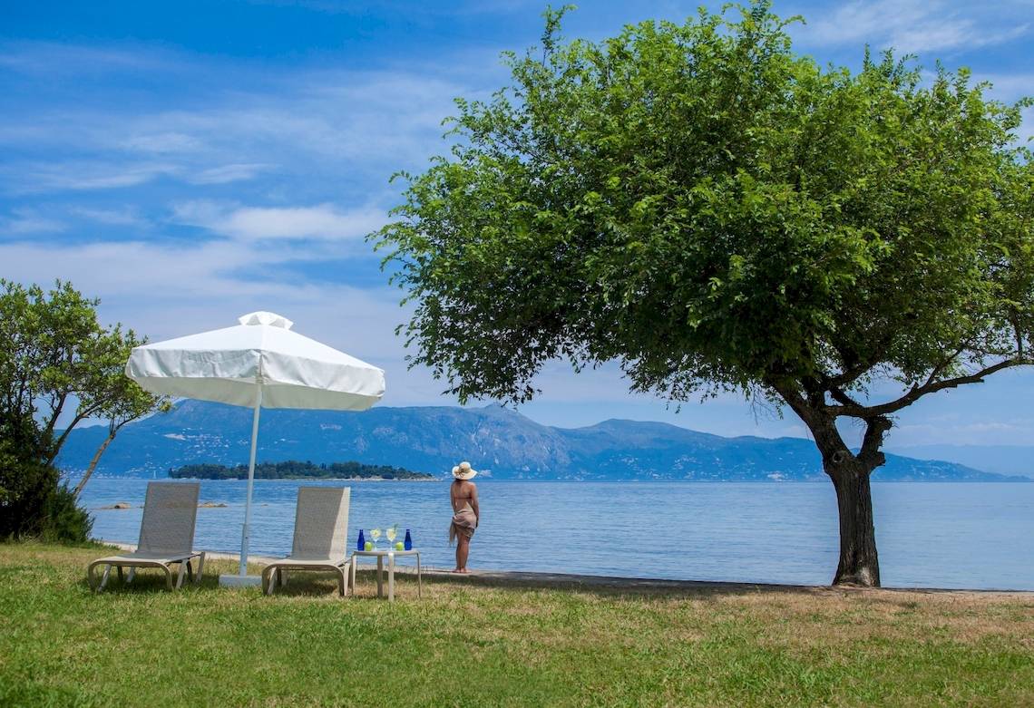 Frau am Strand des Louis Kerkyra Blue Hotels mit Blick auf das Meer und Berge