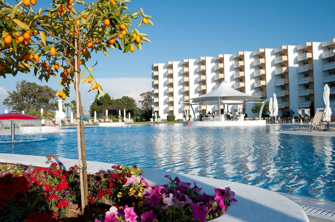 Außenbereich des Louis Kerkyra Blue Hotels mit Swimmingpool und Blumenbeet.