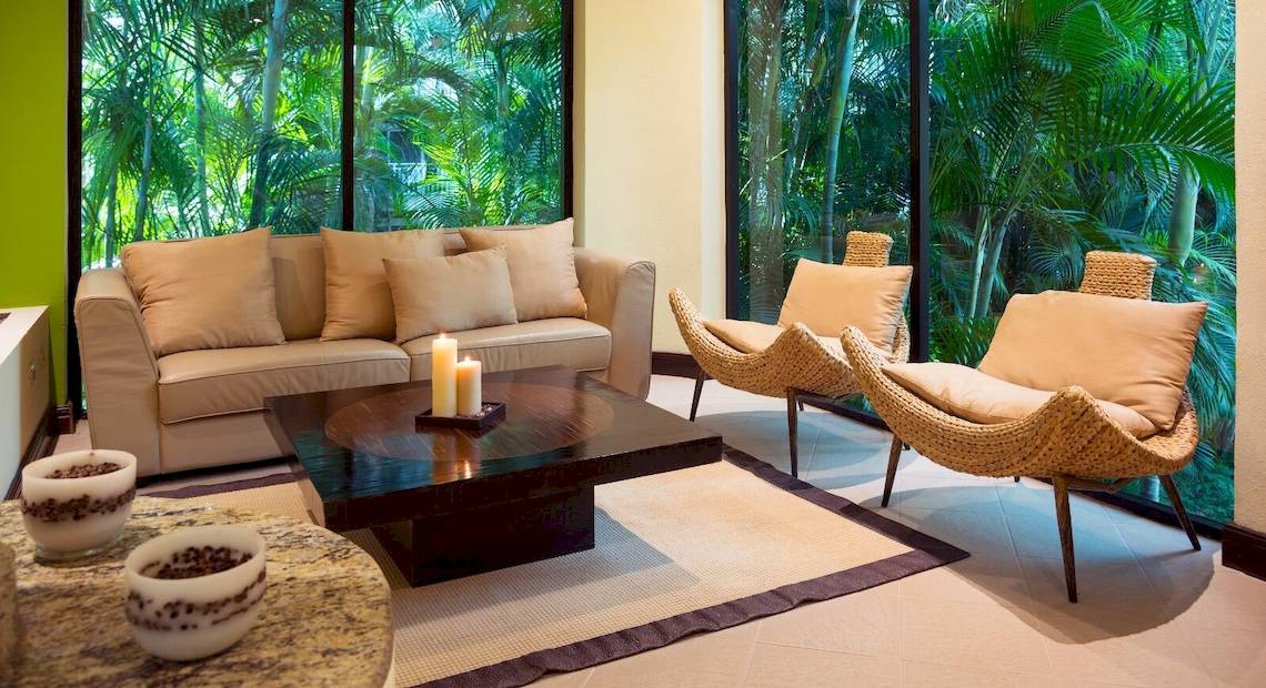 Wohnzimmer im Occidental Tamarindo Hotel mit Couch, Kerzen und Fenstern.