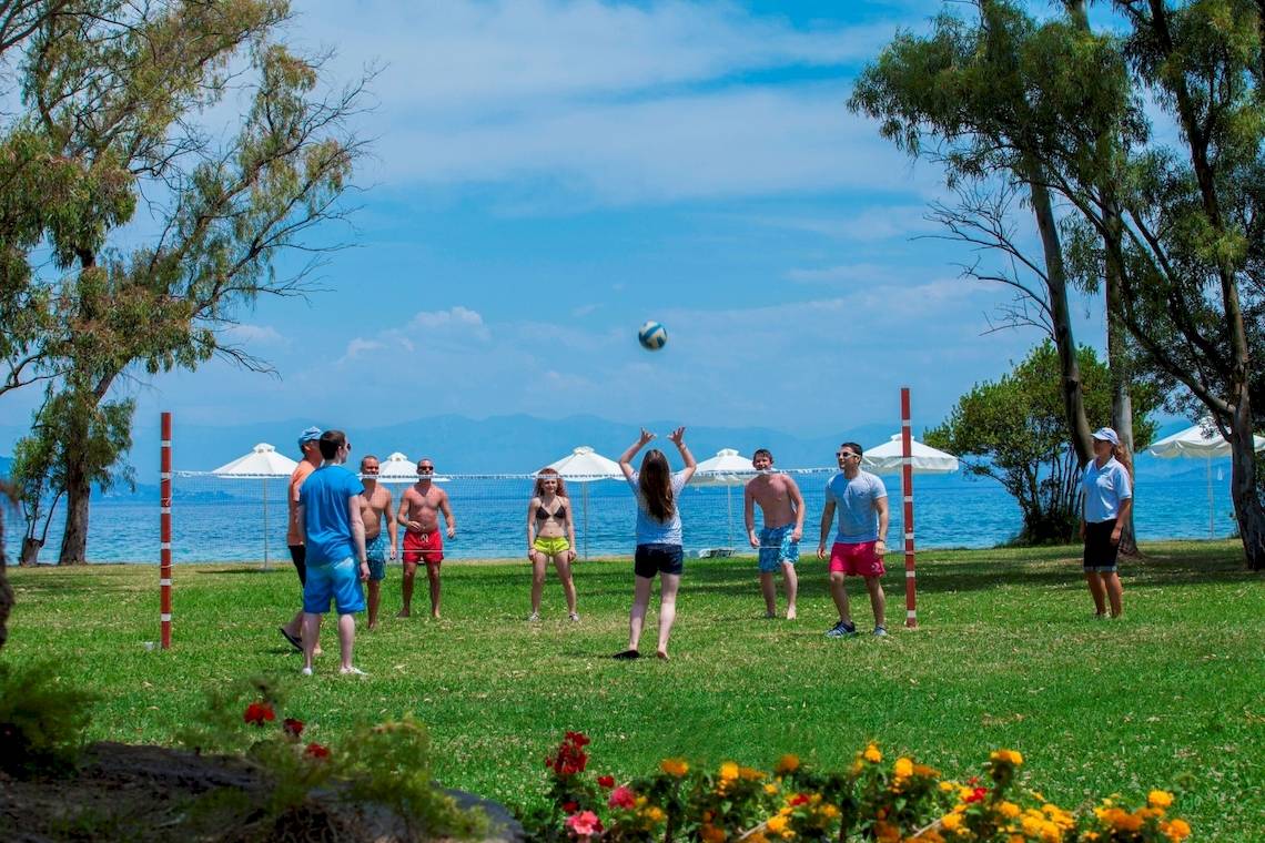 Gruppe spielt Volleyball im Freibad mit Blick auf den Ozean und Palmen