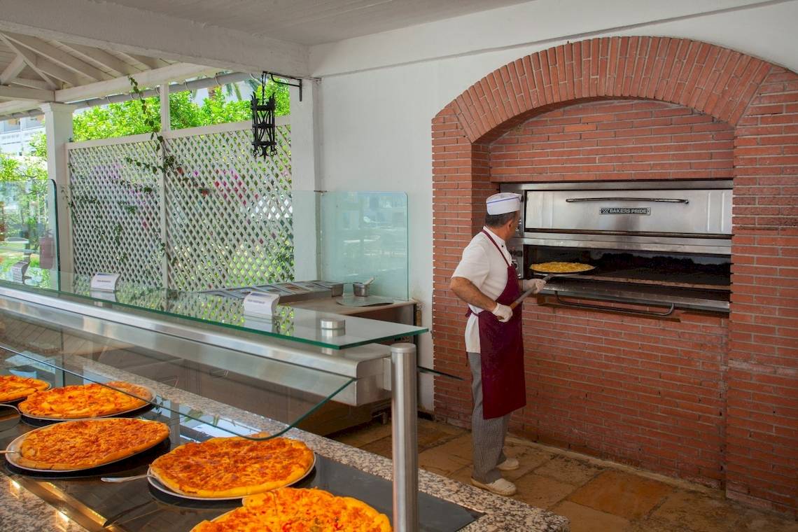Koch in der Küche des Louis Kerkyra Blue Hotel, der Pizza aus dem Ofen nimmt.