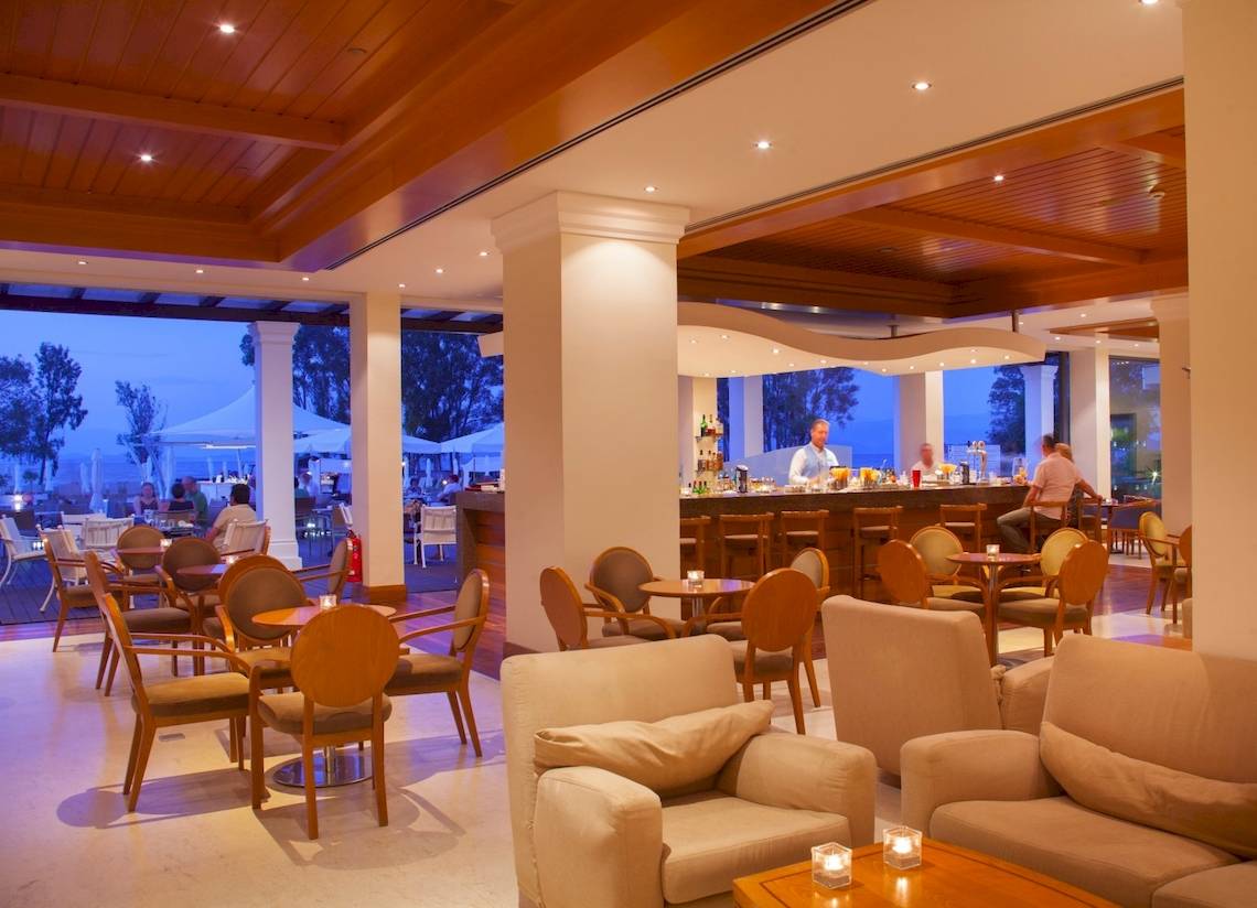 Loungebereich des Louis Kerkyra Blue Hotels mit Bar, Tischen und Stühlen sowie Ausblick auf den Garten.