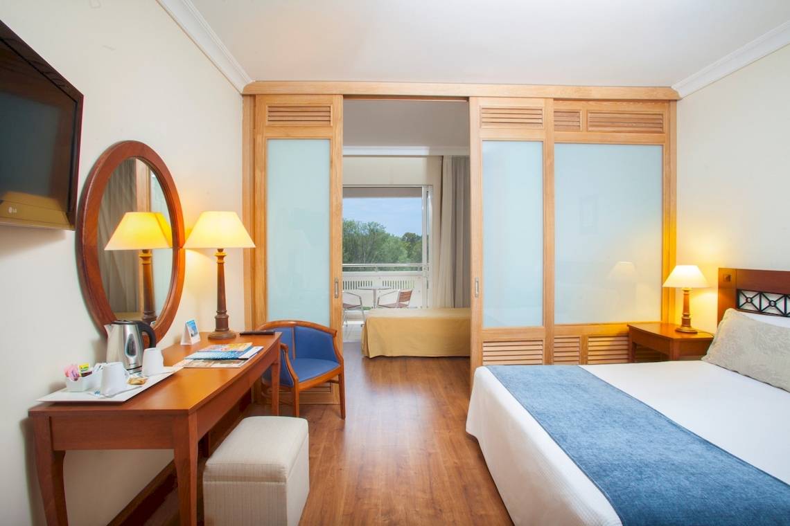 Innenansicht des Louis Kerkyra Blue Hotelzimmers mit Bett, Schreibtisch und Balkonzugang