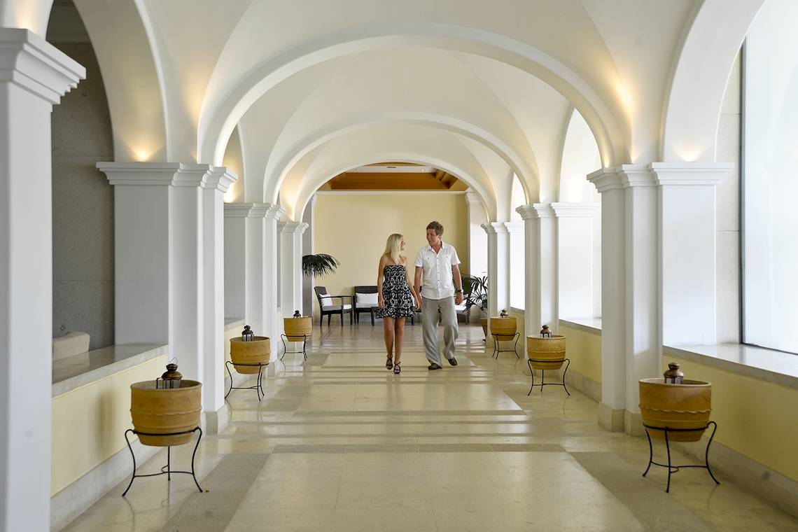 Ein Paar geht durch die geflieste Halle des Louis Kerkyra Blue Hotels.