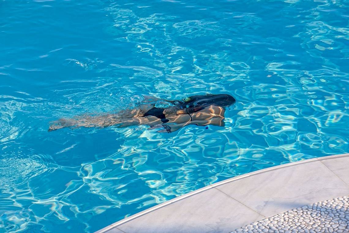 Eine Frau schwimmt in einem blauen Schwimmbad.