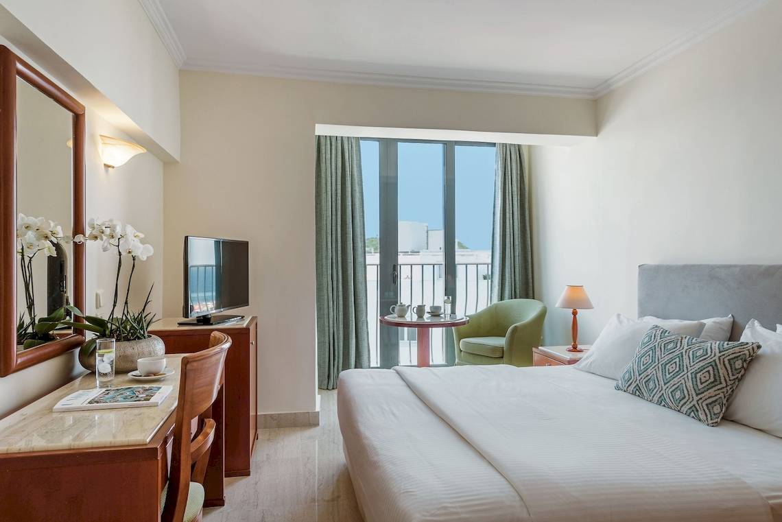 Schlafzimmer im Mitsis La Vita Beach Hotel mit Bett, Schreibtisch und Balkon