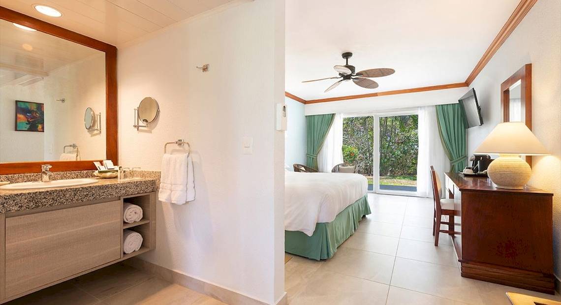 Innenansicht der Suite im Occidental Tamarindo Hotel mit Schlafzimmer und Badezimmer.