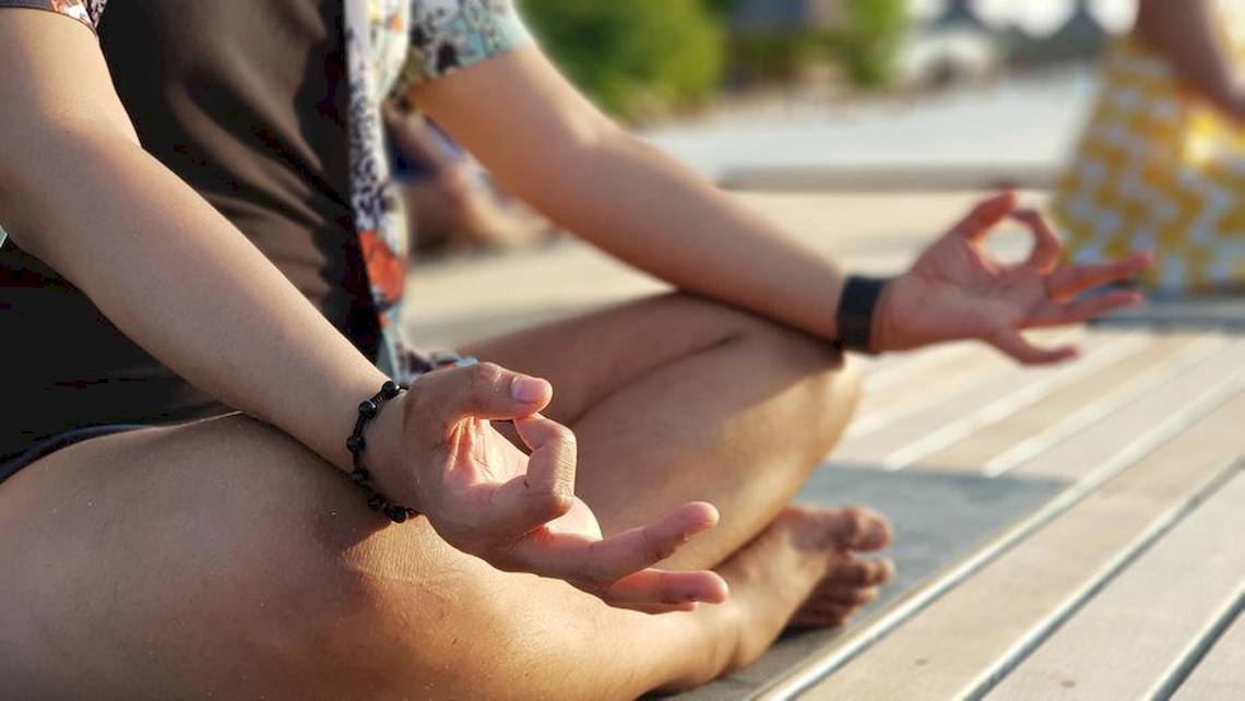 Eine Person praktiziert Yoga und Meditation am Strand des Dhawa Ihuru Hotels.