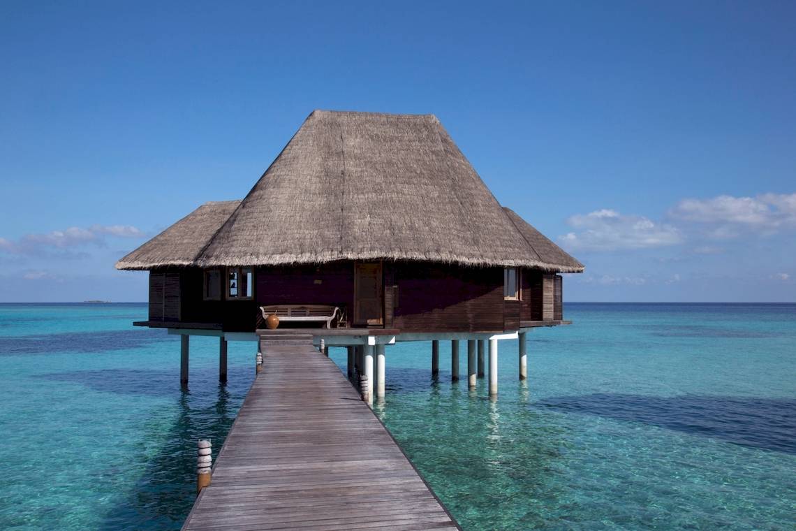 Coco Palm Dhuni Kolhu Überwasser-Bungalow mit Strohdach und Steg im Meer