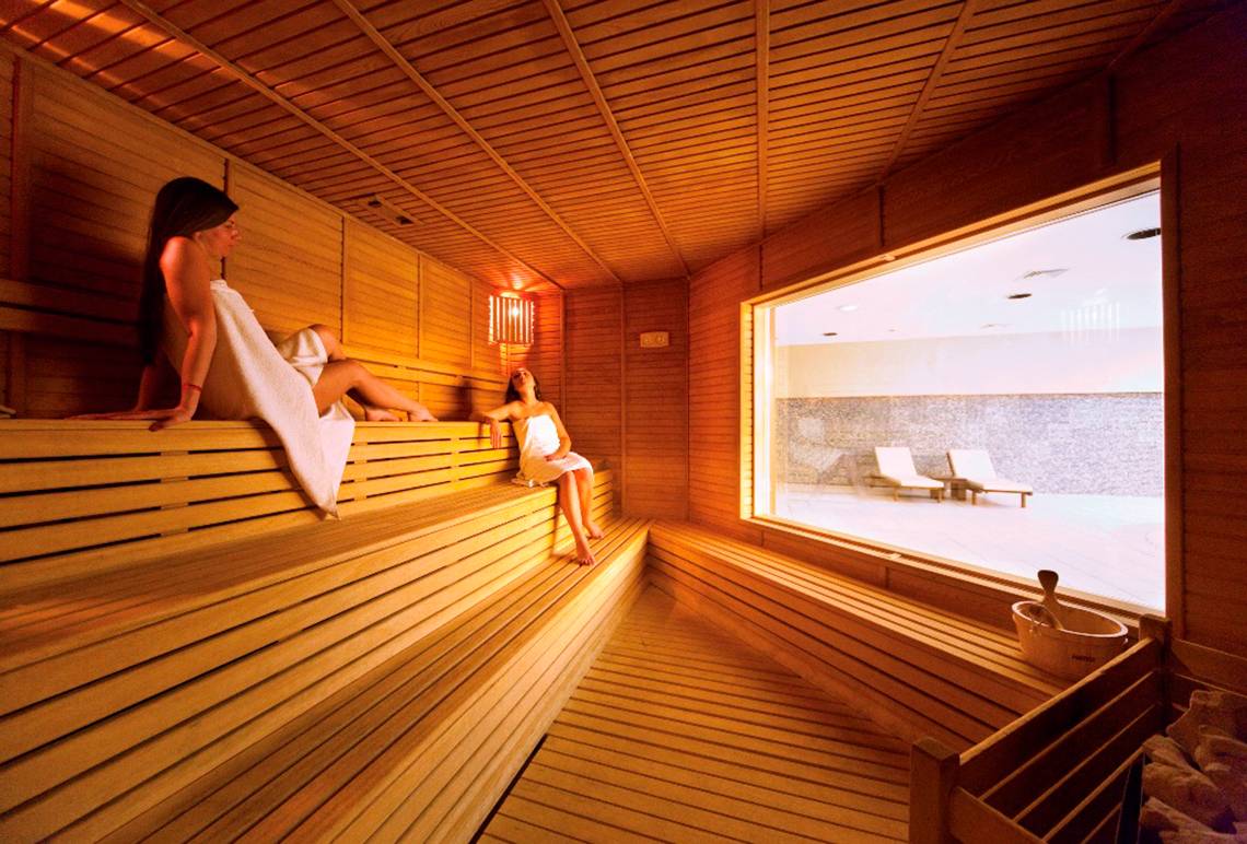 Innenansicht der Sauna im Side Star Resort mit zwei Frauen auf Holzbänken