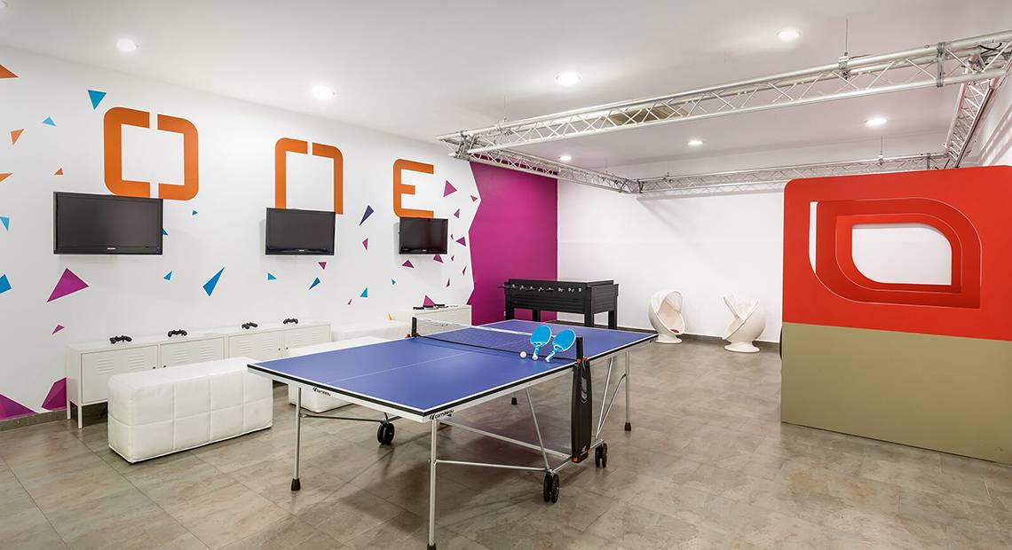 Spielzimmer im Barcelo Santiago Hotel mit Tischtennistisch, Fernsehern und bunten Wänden.