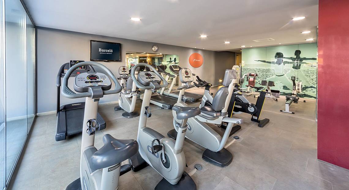 Fitnessbereich im Barcelo Santiago Hotel mit modernen Trainingsgeräten und einer großen Wandgrafik.