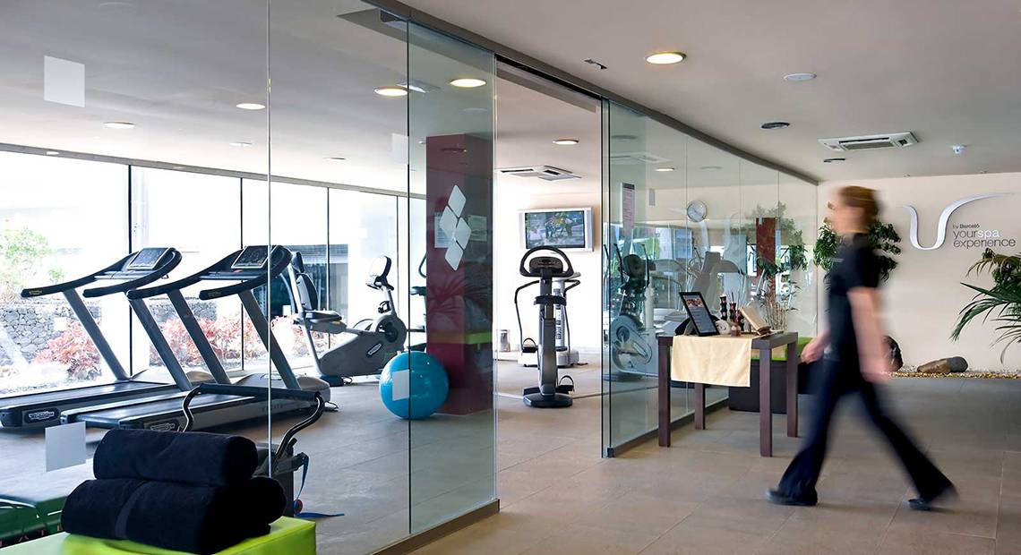 Fitnesscenter im Barcelo Santiago Hotel mit Laufbändern, Trainingsgeräten und einer Person, die vorbeigeht.
