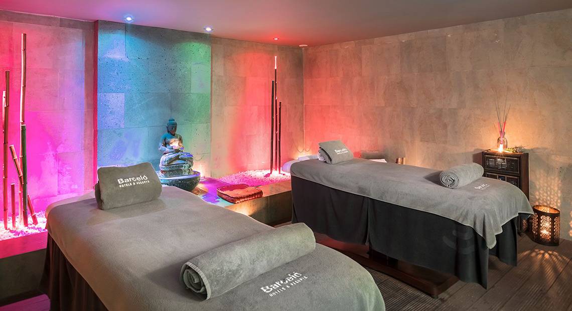 Behandlungsraum im Barcelo Santiago Hotel Spa mit zwei Massagetischen und bunten Lichtern.