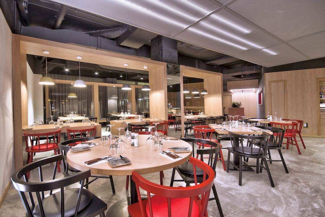 Innenbereich des Restaurants im Doubletree by Hilton Malta mit runden Tischen und Stühlen.