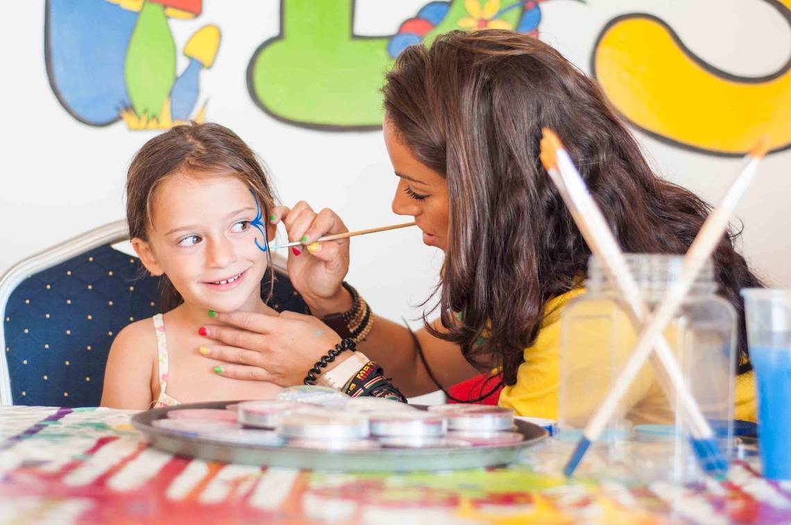 Eine Frau schminkt ein Kind bei einer Schminkparty im Doubletree by Hilton Malta.