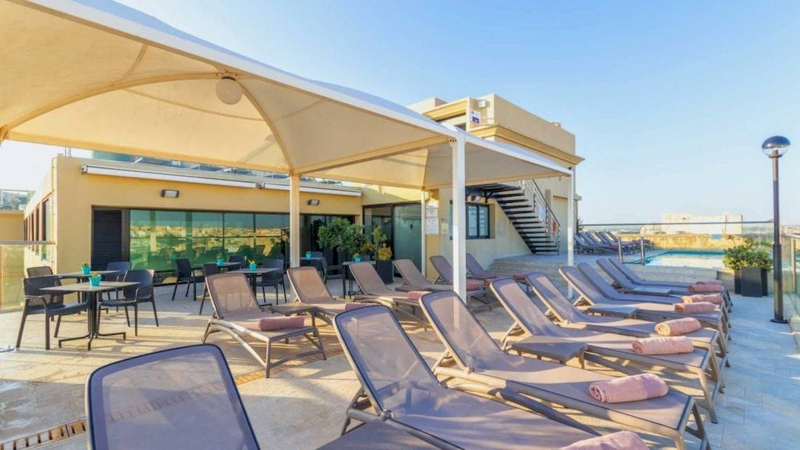 Dachterrasse des AX The Victoria Hotels mit vielen Sonnenliegen und Tischen.