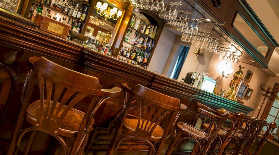 Innenansicht der Bar im AX The Victoria Hotel mit Holzstühlen und Tresen.