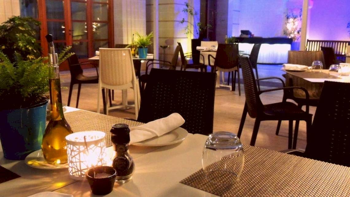 Ein Restauranttisch im AX The Victoria Hotel mit Kerzen, Flaschen und Geschirr.