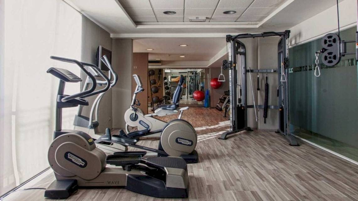 Fitnessraum im AX The Victoria Hotel mit Laufbändern, Rudergeräten und Hanteln.