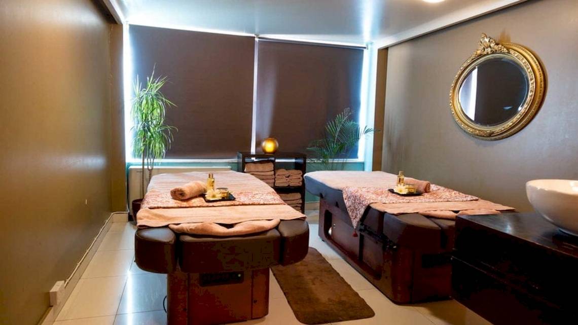 Behandlungsraum im AX The Victoria Spa mit zwei Massagetischen, Spiegel und Pflanzen.