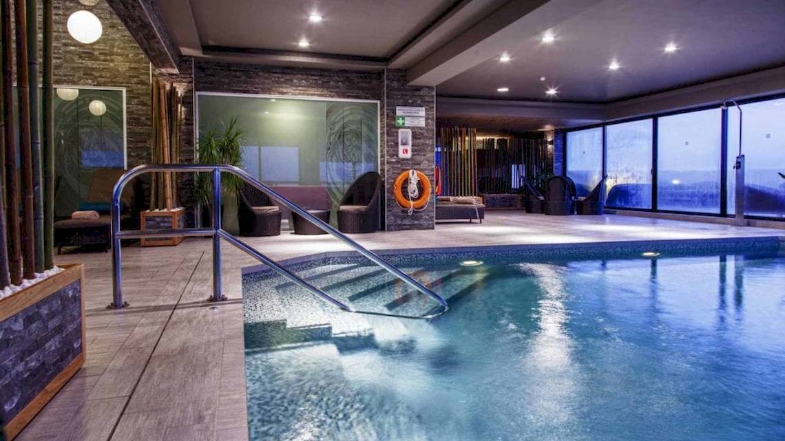 Poolbereich im AX The Victoria Hotel mit Glaswänden und Inneneinrichtung.
