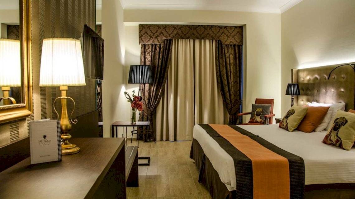 Hotelzimmer im AX The Victoria mit Bett, Lampen und Dekor.