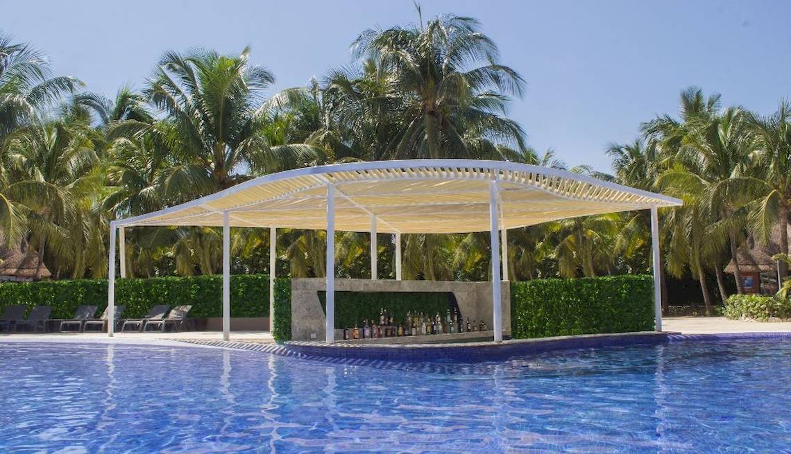 Poolbar im Catalonia Playa Maroma Hotel mit Blick auf einen Pool und Palmen im Hintergrund.