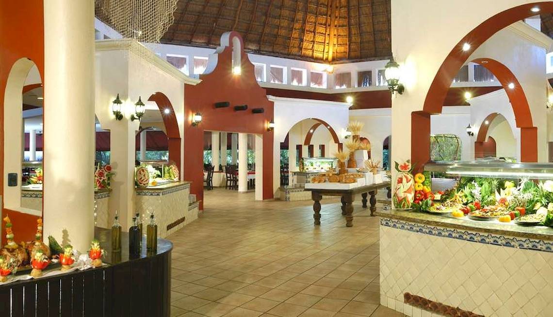 Innenbereich des Catalonia Playa Maroma Hotels mit Speisenbuffet und dekorativen Elementen.
