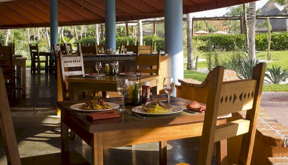 Esstisch im Restaurant des Hotels Catalonia Playa Maroma mit Speisen, Gläsern und Dekor.