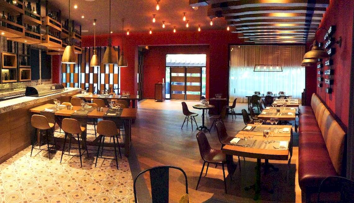 Innenansicht des Restaurants Catalonia Playa Maroma mit roten Wänden, Holzböden und modernen Möbeln.