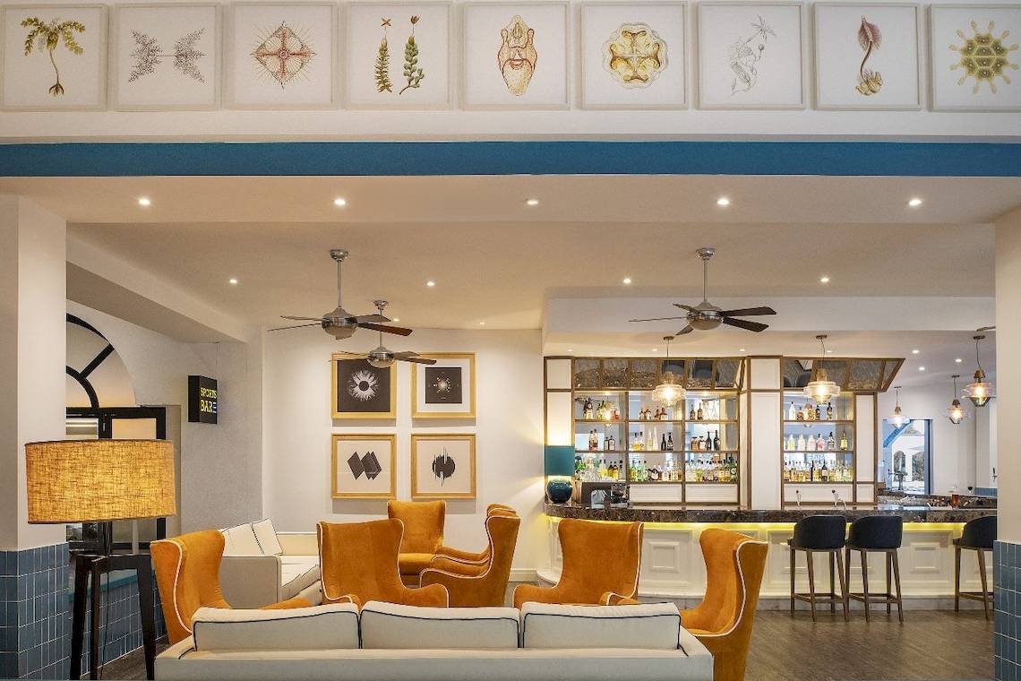 Innenbereich der Bar im Ocean Maya Royale Hotel mit orangefarbenen Sesseln und Theke.