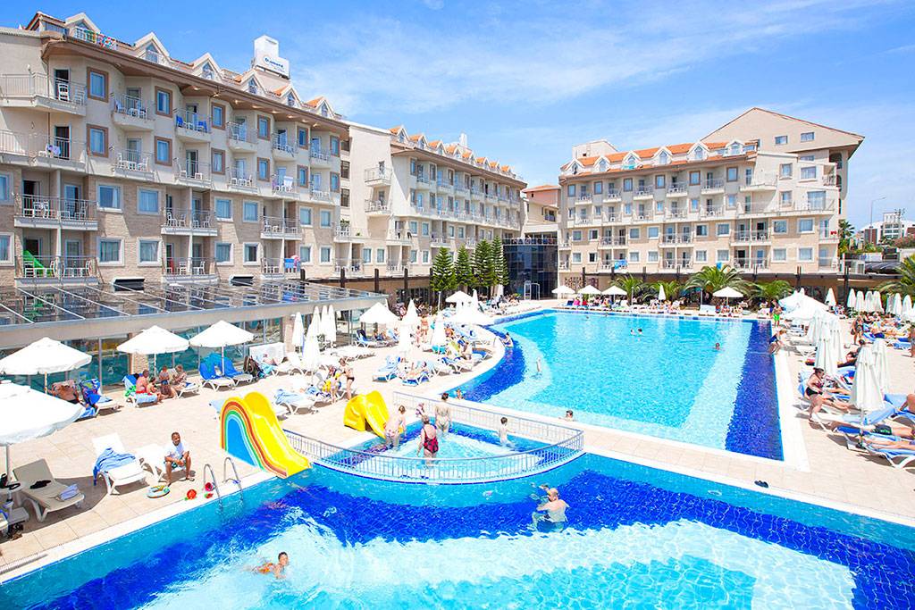 Poolbereich des Side Aluna Hotels mit vielen Gästen, Sonnenliegen und Sonnenschirmen