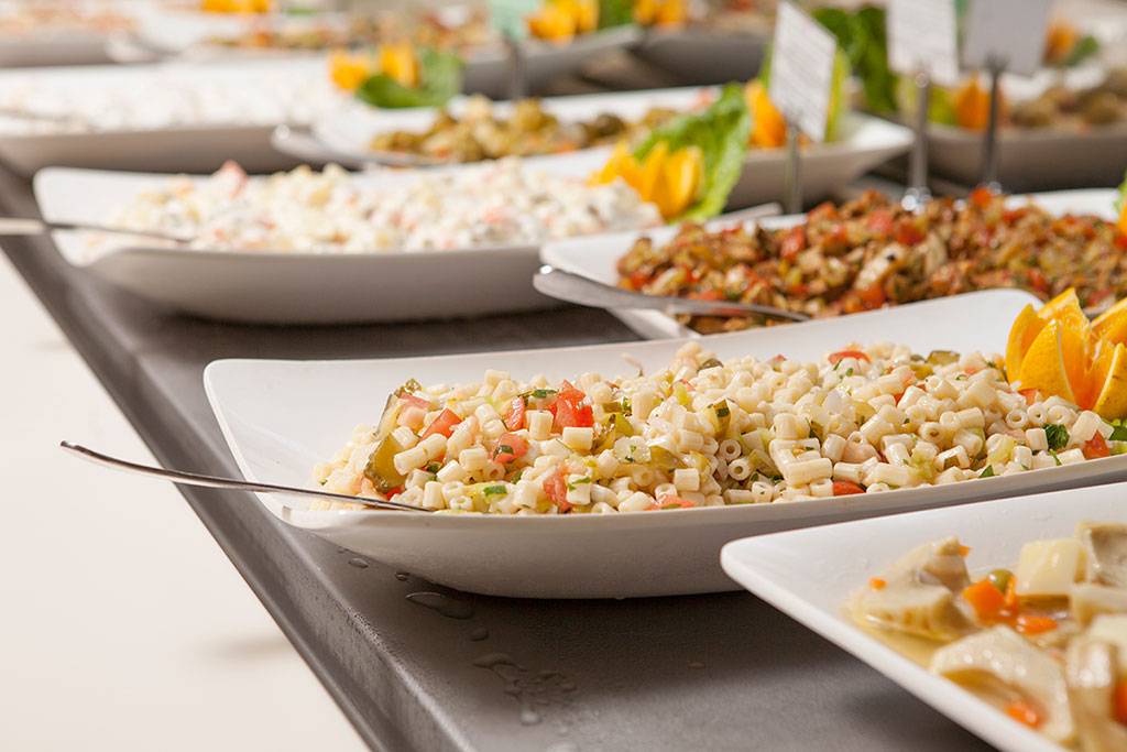 Buffet mit verschiedenen Gerichten im Side Aluna Hotel, darunter Nudeln, Salate und andere Speisen in weißen Tellern.