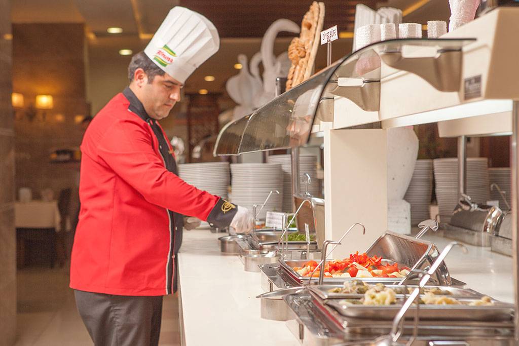 Koch im Side Aluna Hotel serviert Speisen am Buffet.