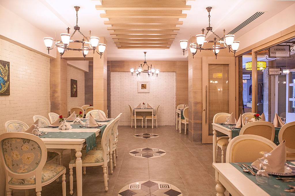 Innenansicht des Restaurants des Side Aluna Hotels mit gepflegten Tischen, Stühlen und Kronleuchtern.