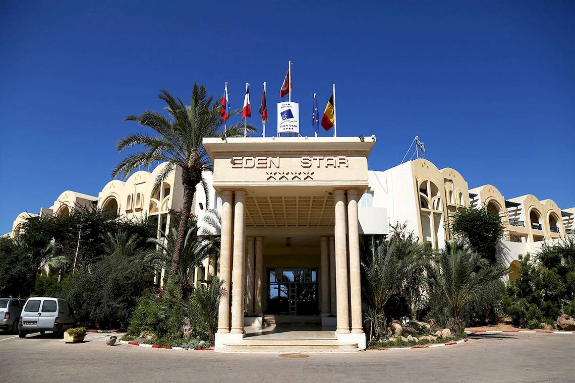 Eingang des Eden Star Zarzis Hotels mit Palme und Flaggen.
