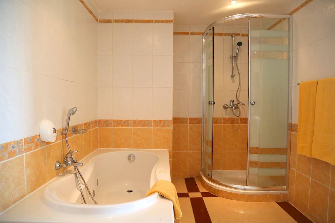 Badezimmer mit Badewanne und Dusche im Eden Star Zarzis Hotel, mit gelben Fliesen und blauem Boden.