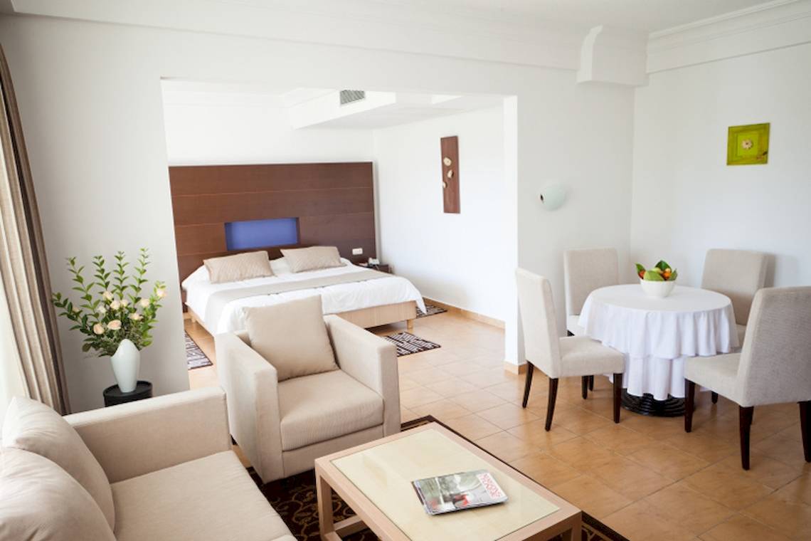 Innenansicht der Suite im El Mouradi Club Kantaoui mit Bett, Wohnzimmer und Essbereich.