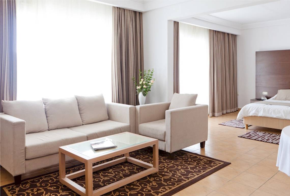 Schlafzimmer im El Mouradi Club Kantaoui Hotel mit einem Bett, Sofas und einem Tisch.