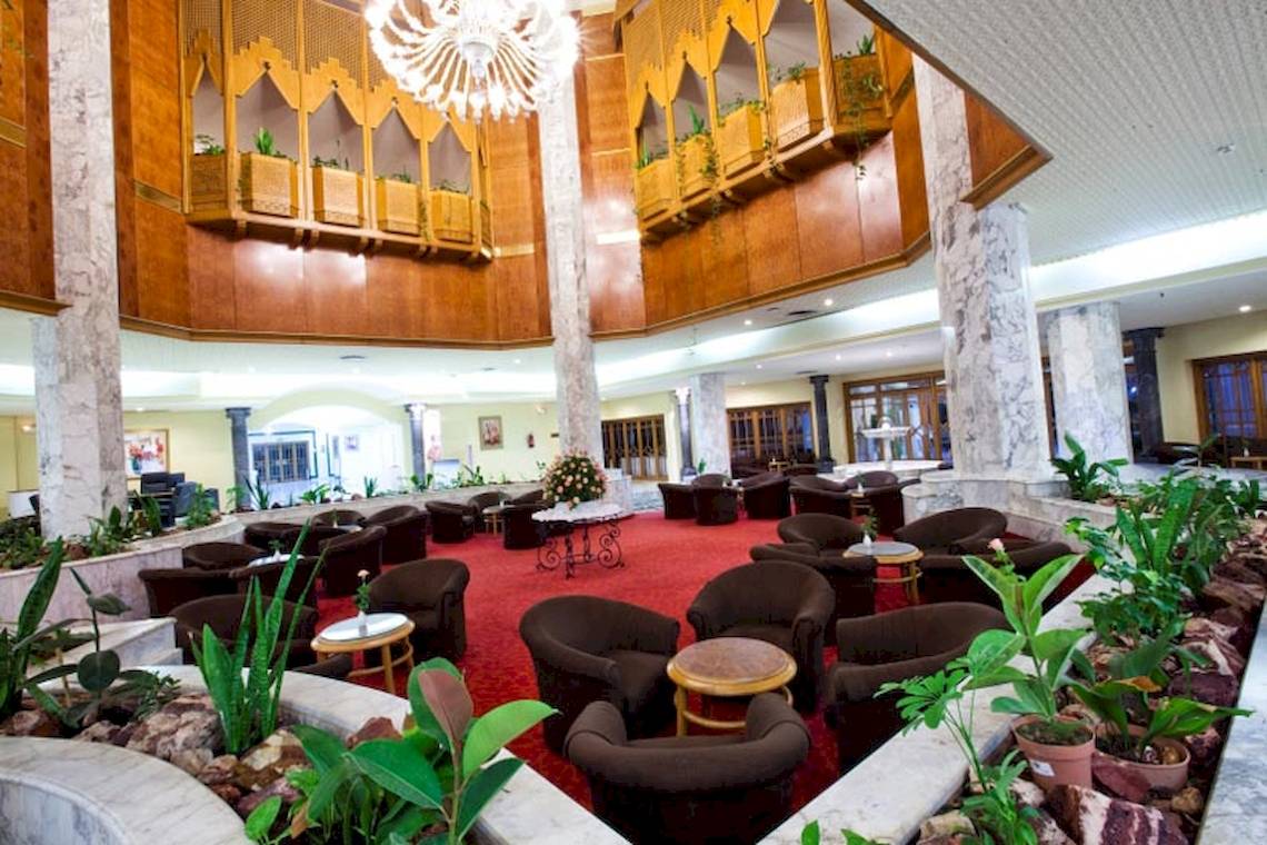 Foyer des El Mouradi Palace Hotels mit roten Teppichen, Sofas und Pflanzen