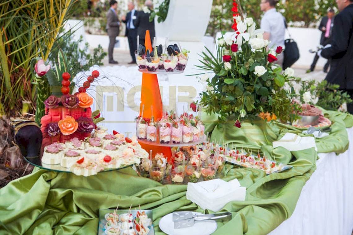 Buffet mit verschiedenen Speisen und Blumen auf einer Veranstaltung.