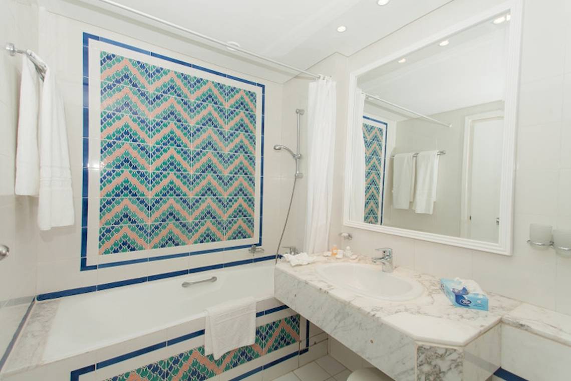 Badezimmer des El Mouradi Palace Hotels mit Badewanne und blauen Kacheln